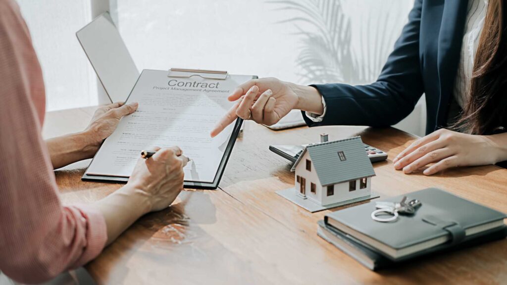 This image depicts a mortgage broker in Bend, Oregon, guiding a client through the process of signing a renovation mortgage contract.