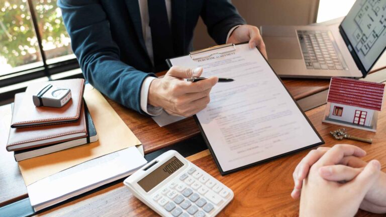 This image shows a mortgage broker in Bend, Oregon, demonstrating loan calculations to a client before presenting the contract for signing.